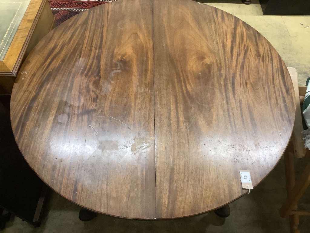 A 1920's circular mahogany extending dining table with three leaves and handle, length approx. 230cm